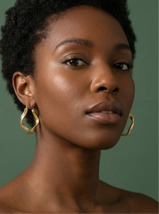 Woman wearing gold hoop earrings against a green background
