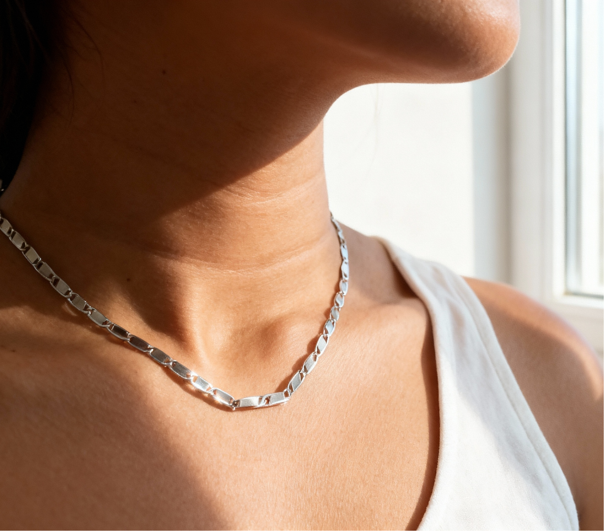 Silver necklace worn by a person with a blurred background
