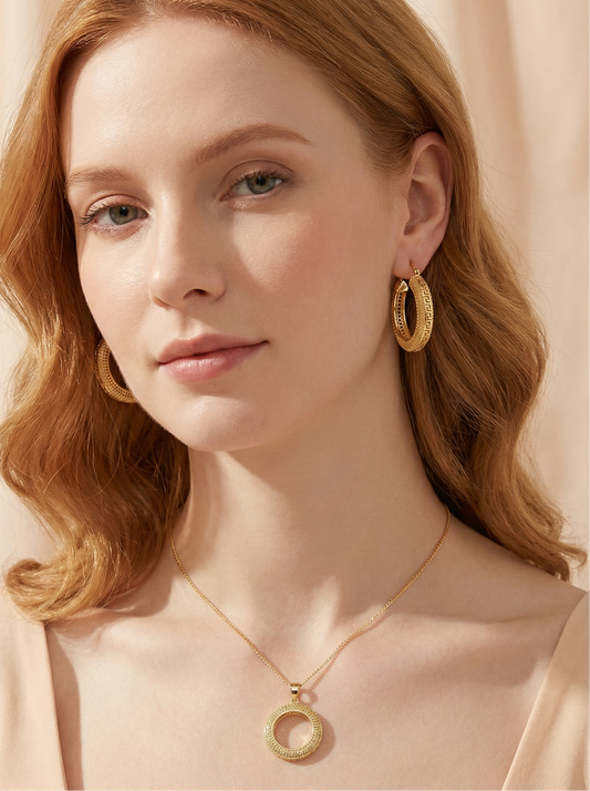 Woman wearing gold hoop earrings and necklace against a beige background