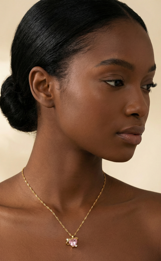 Woman wearing a gold necklace with a pink pendant against a beige background